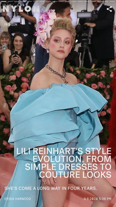 Actress, Lili Reinhart posing on a red carpet wearing a puffy blue dress and large flower in her hair 