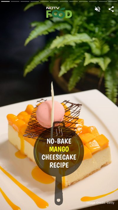 A cheesecake with fresh diced mangos on top with chocolate drizzle and a pink macaroon used for garnish 