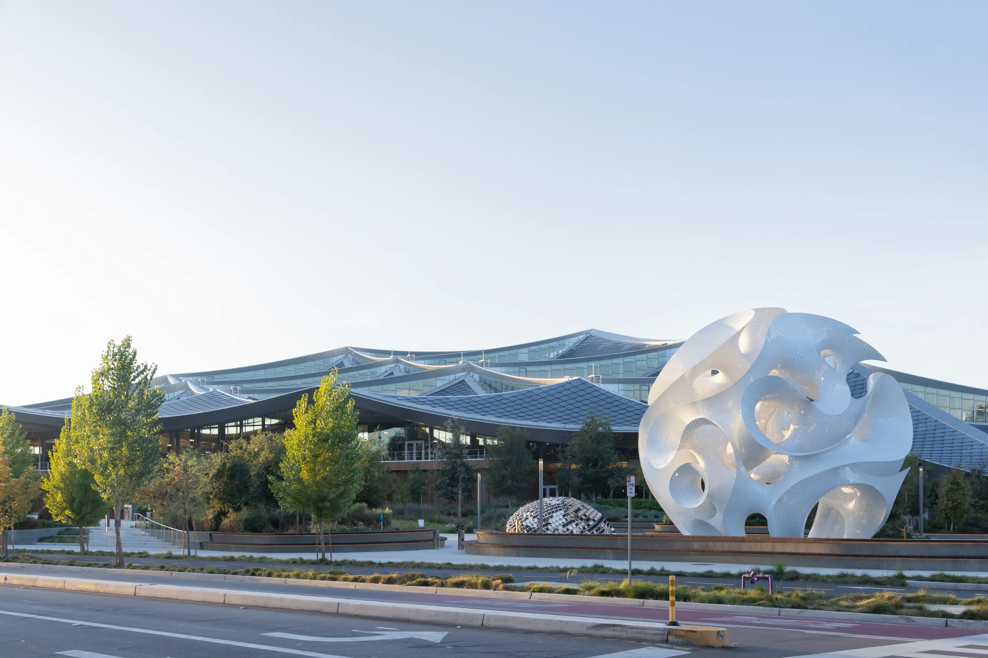 A photo of  an orb-like ultra-thin, self-supporting aluminum sculpture in front of a Google office.