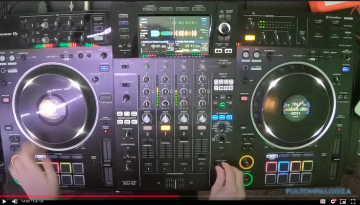 A DJ booth with two hands adjusting multiple buttons and knobs.