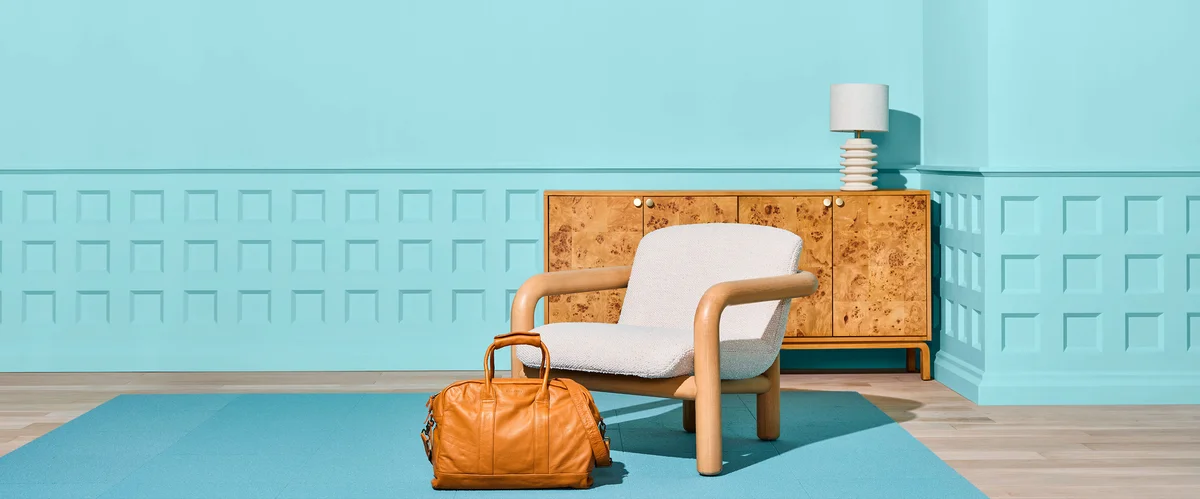 An arm chair is shown with a credenza and weekender bag.