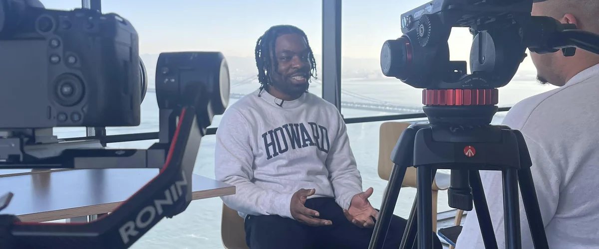 A man in a Howard sweatshirt speaks to a camera during an interview.