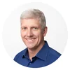 Rick Osterloh, wearing a dark blue button-down shirt, smiles at the camera
