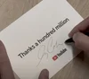 YouTube Global Head of Music Lyor Cohen signing postcards that say, "Thanks a hundred million."