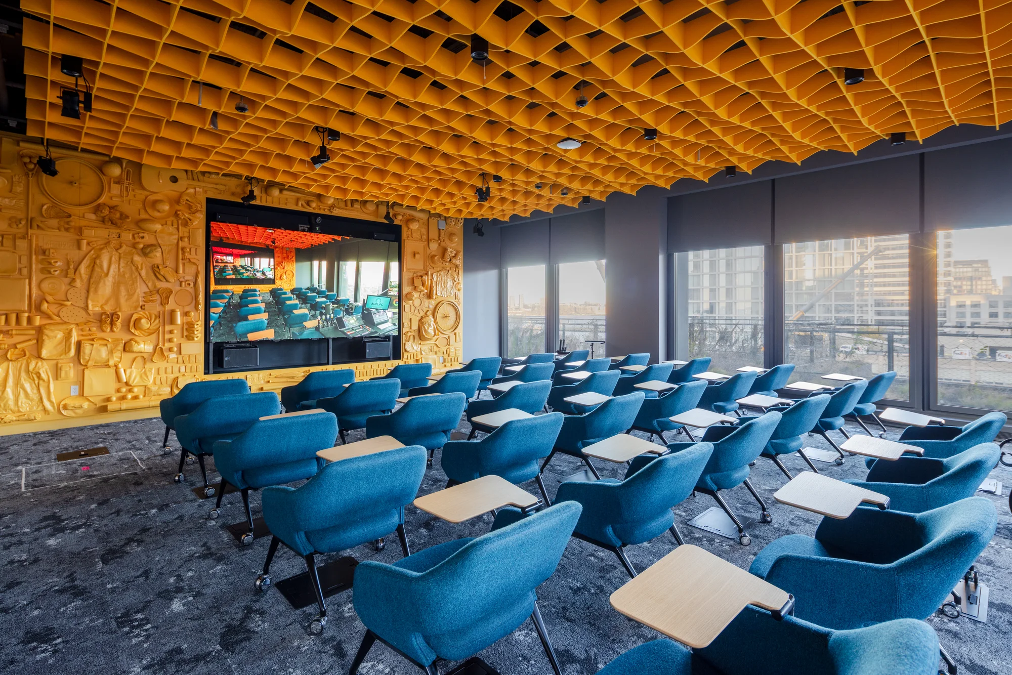 A conference room with classroom style seating, blue chairs and bright yellow walls and ceiling.