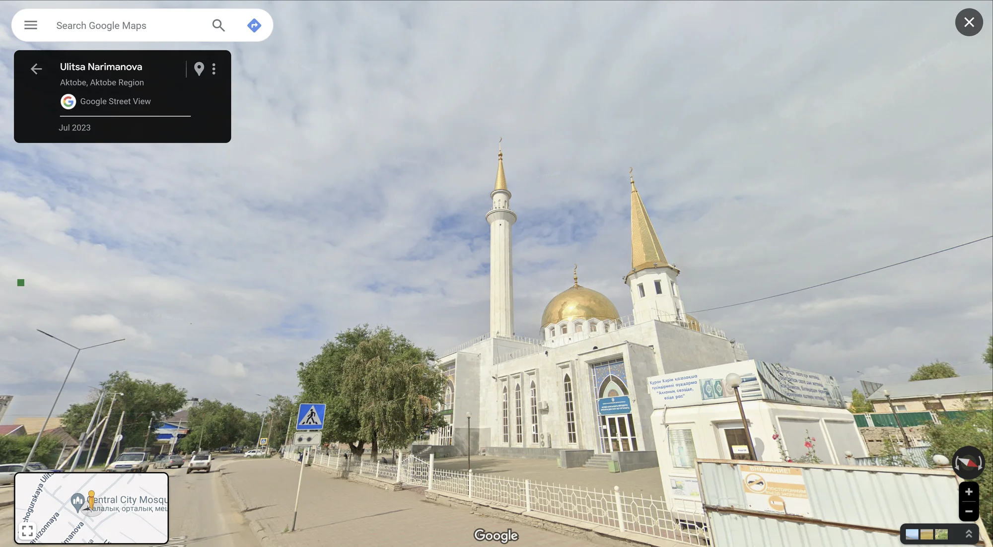 The Aktobe Central Mosque, with a golden roof and a cloudy sky behind it