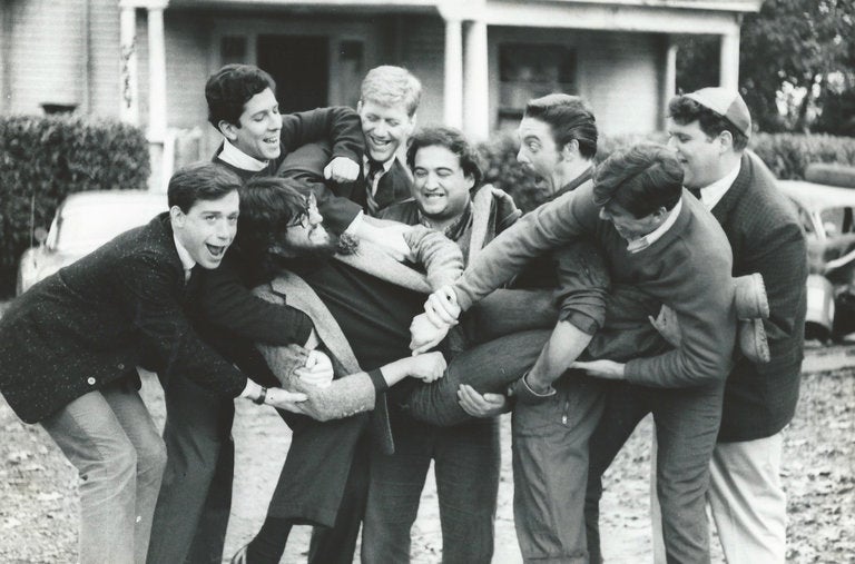 The set was as high-spirited as the film. The cast members, from left: Tom Hulce, Peter Riegert, James Widdoes, John Belushi, Bruce McGill, Tim Matheson and Stephen Furst with their director, John Landis.