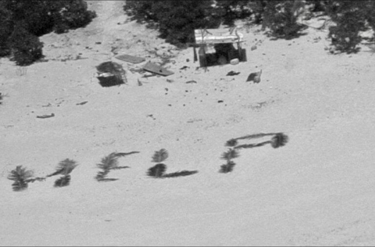 In this image provided by the U.S. Coast Guard, the word “help” is written in palm fronds on the beach of a small island in Micronesia.