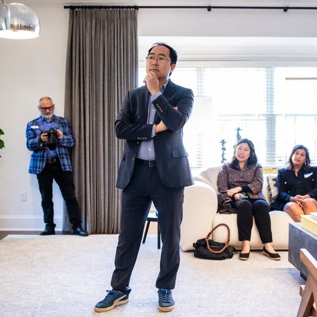Representative Andy Kim, in a blue suit and running shoes, listens to questions from voters at a home in Montclair, N.J.