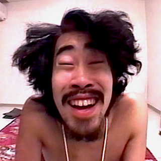 Nasubi smiling and looking into the camera in a still of the Japanese reality show “Susunu! Denpa Shonen” in 1998.