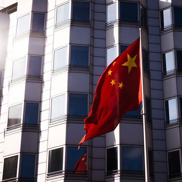 A Chinese flag in front of a modern gray building.