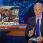 Jon Stewart sits behind a news desk, holding up one finger. Beside him is an inset photo of Donald Trump in a courtroom.