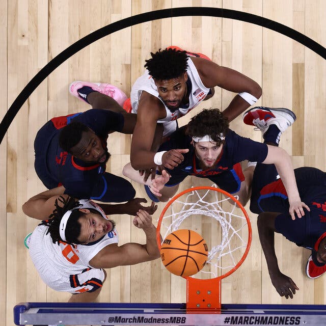 Seen from above, five basketball players under a hoop get ready for a possible rebound.