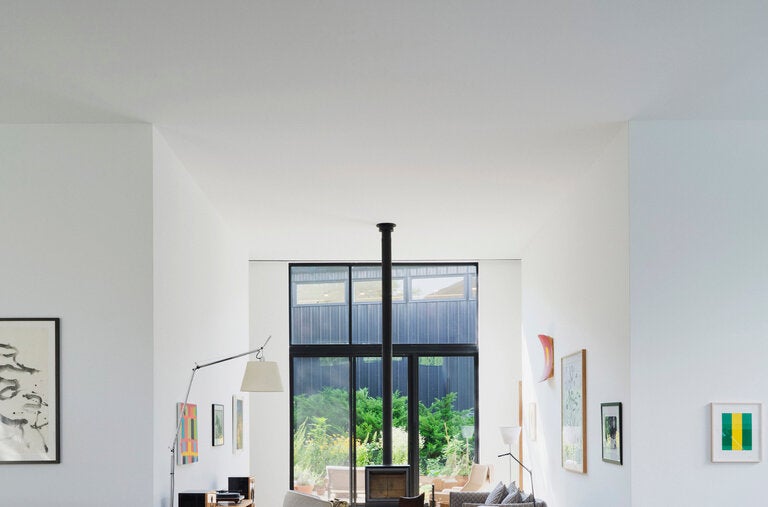 The expansive main room of the artists Stanley Whitney and Marina Adams’s Bridgehampton, N.Y., home has 16-foot-high ceilings and a seating area anchored by a cast-iron stove.